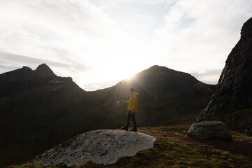 Man on Veinestinden hiking trail in Lofoten, Norway.  Located in the Arctic circle.  Sun setting...