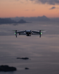 Drone hovering at top of Reinebringen mountain hike in Lofoten, Norway.  Snow covered mountains captured on image by Sony mirrorless camera.  Located far North in the Arctic Circle.