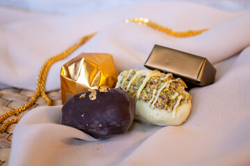 Golden Necklace and Chocolate Pieces on White Background with Elegant Mock-Up Space. Luxury Concept for Jewelry and Chocolates. Perfect for Celebrations, Gifts, and Events. with Copy Space