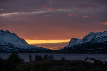 Beautiful orange and pink sunset between two snowcapped mountain peaks in Tromso, Norway.  Located...