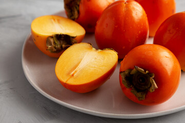 Organic Persimmon Fruit on a Plate on a gray background, low angle view. Close-up.