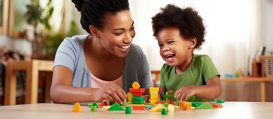 An African child plays with educational toys while supported by his mother and kindergarten teacher copy space image - obrazy, fototapety, plakaty