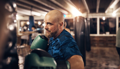 Mature man hitting a punching bag in a boxing gym