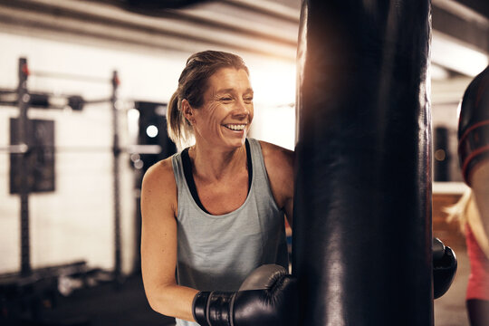 Mature woman laughing while exercising with a boxing gym punching bag