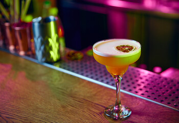 Angle view of fresh sweet and sour cocktail, alcohol drink decorated with dry citrus stands on bar counter at club or restaurant.