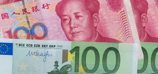 100 euro and 100 yaun bills on desk.