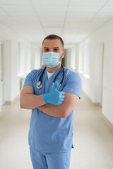 Fototapeta na wymiar caucasian male doctor in a blue coat and a medical mask at hall of clinic