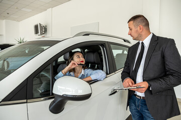 Customer buying a modern car with help a professional male manager at car dealership