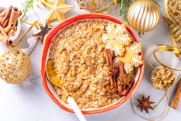 Christmas morning gingerbread oatmeal breakfast. Spice sweet oatmeal with gingerbread crumbs, cinnamon and honey, on festive decorated background copy space