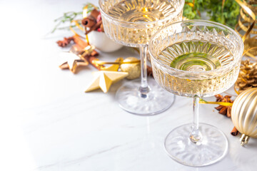 Two champagne glasses on Christmas decorated background, Merry Christmas and Happy New Year greeting card background, with golden baubles and fir tree branches
