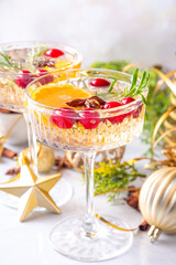 Christmas champagne fruit punch with cranberry, orange, spices and rosemary. Sweet alcohol cocktail glasses, on Christmas and New Year decorated background
