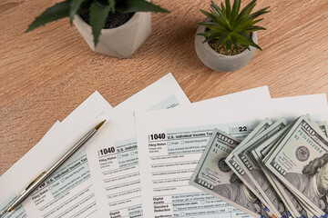 Fototapeta na wymiar Income tax return 1040 forms with blue pen and us dollar bills at office desk