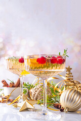 Christmas champagne fruit punch with cranberry, orange, spices and rosemary. Sweet alcohol cocktail glasses, on Christmas and New Year decorated background