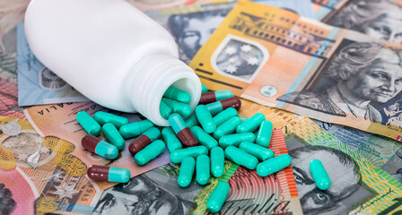Green capsules dispersed from bottle on australian dollars