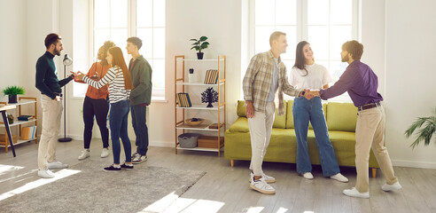 Diverse group of cheerful smiling people friends or coworkers meeting in the living room together, talking and sharing news and stories with each other gathering at party at home. Banner.