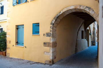 Fototapeta na wymiar Crete island, Chania Old Town, Greece. Building over arched stonewall that covers paved alley.