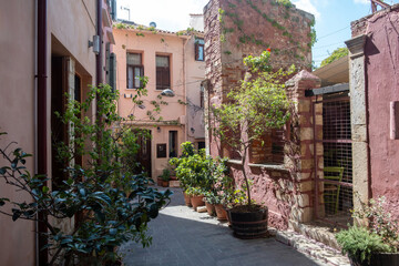 Crete island Chania Old Town Greece. Traditional building, pot with plant on paved alley, sunny day.