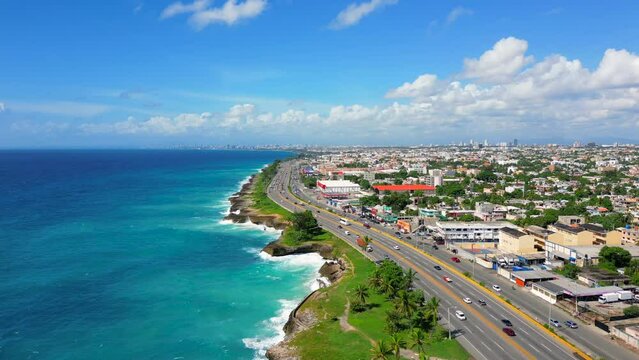 Aerial flight above The Autopista Las Americas along the rocky seacoast. Turquoise caribbean sea and huge waves crashing on the shore. Expressway from the Punta Cana to the Santo Domingo este 