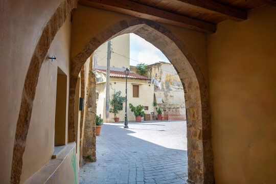 Greece Crete island, Chania Old Town. Arched stonewall covers paved alley and drives to empty yard.