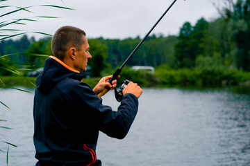Fisherman with fishing rod or spinning rod and professional tools sitting on the river bank Pull fish out of the lake sport fishing