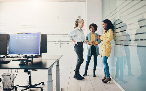 Three diverse businesswomen laughing together in an office