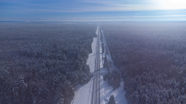 Top view of train track rails crossing through snowy forest in winter near Munich