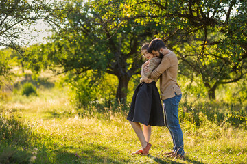 young couple, illuminated by the backlit sun, hugging in nature