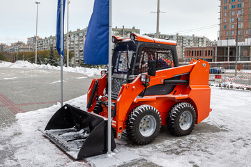 Skid-steer loader in a parking lot in the city on a winter day