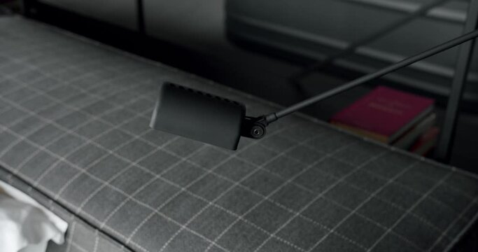 Closeup of adjustable small lamp for reading near headboard on bed. Modern night light in bedroom. Decoration element in apartment with minimalist design