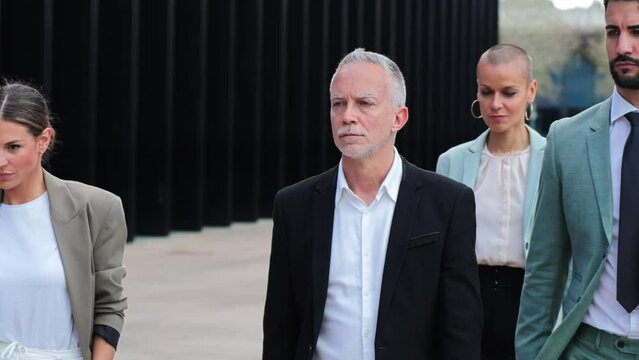 Slow motion 4k fotage of a group of business people walking with determination at downtown workplace. Front view of a serious white collar worker with his partners. Salesman with office collegagues