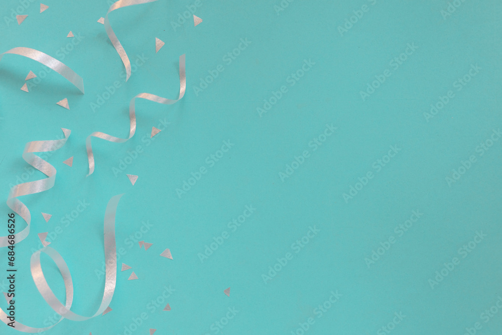 Wall mural close up on group of silver color of rolling ribbon and confetti on teal background with copy space 