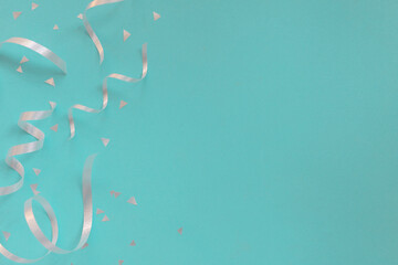 close up on group of silver color of rolling ribbon and confetti on teal background with copy space for christmas festival happy new year ,carnival , birthday and anniversary, concept design
