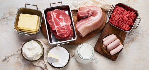 Saturated fats on tables. Raw meat, sausages, cheese, butter. Bad food concept