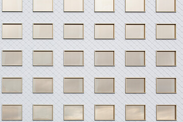 Moderne Fassade mit goldenen Fensterrahmen und weißen Schindeln. Architektur mit verspiegelnden...