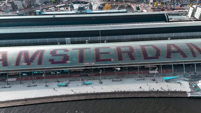 Aerial drone view Amsterdam Central Train Station with Amsterdam sign on roof. Bird's eye view autumn cityscape. High quality 4k footage