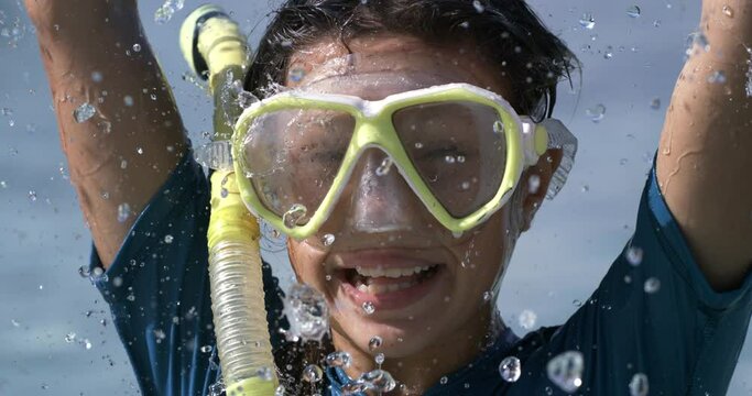 Super slow motion of happy smiling little girl wearing diving suit and snorkel mask while having fun at sea during summer holidays family travel vacation.