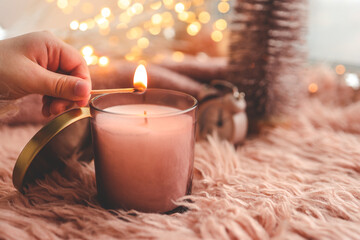 A match lights a candle close-up, Christmas mood in pink colors