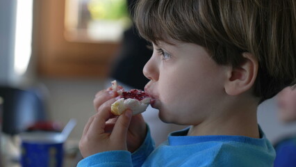 Little Caucasian Boy Enjoying Brioche with Jelly at Breakfast, Child Relishing Morning carb food