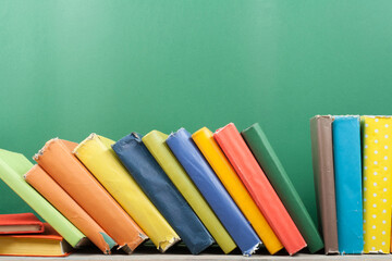 Book stacking. Open hardback books on wooden table and green background. Back to school. Copy space...