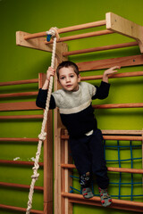 A boy on a Swedish wall. Indoor sports. Boy doing sports on horizontal bars