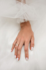 tender hand of the bride with a wedding ring on the background of a white wedding dress