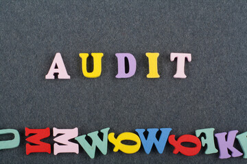 AUDIT word on black board background composed from colorful abc alphabet block wooden letters, copy space for ad text. Learning english concept.