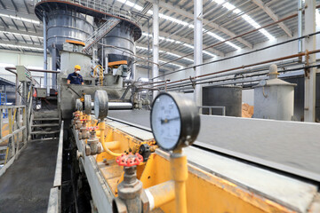 Workers work nervously on the production line of new building materials calcium silicate board,...