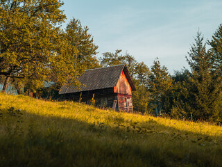 Old authentic wooden house with hayloft in scenic Carpathian mountains Ukraine, Europe, Transcarpathia region. Local countryside travel forest hiking trails. Cottagecore style vacation. Eco tourism.