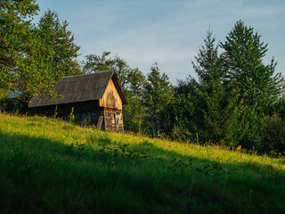 Fototapeta premium Old authentic wooden house with hayloft in scenic Carpathian mountains Ukraine, Europe, Transcarpathia region. Local countryside travel forest hiking trails. Cottagecore style vacation. Eco tourism.