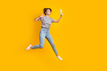 Fototapeta na wymiar Full length portrait of excited person jump smart phone take selfie show thumb up empty space isolated on yellow color background
