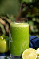 Healthy green smoothie with lime and apple in the garden.