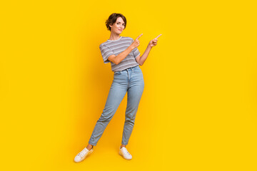 Full length portrait of lovely positive person indicate fingers empty space offer isolated on yellow color background