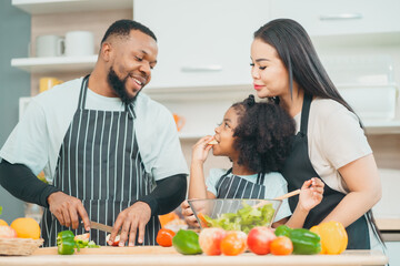 Kind African american parents teaching their adorable daughter how to cook healthy food, free space of kitchen, Happy black people family preparing healthy food in kitchen together