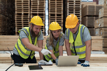 Group of male and female warehouse workers working laptop computer at wooden warehouse storage....